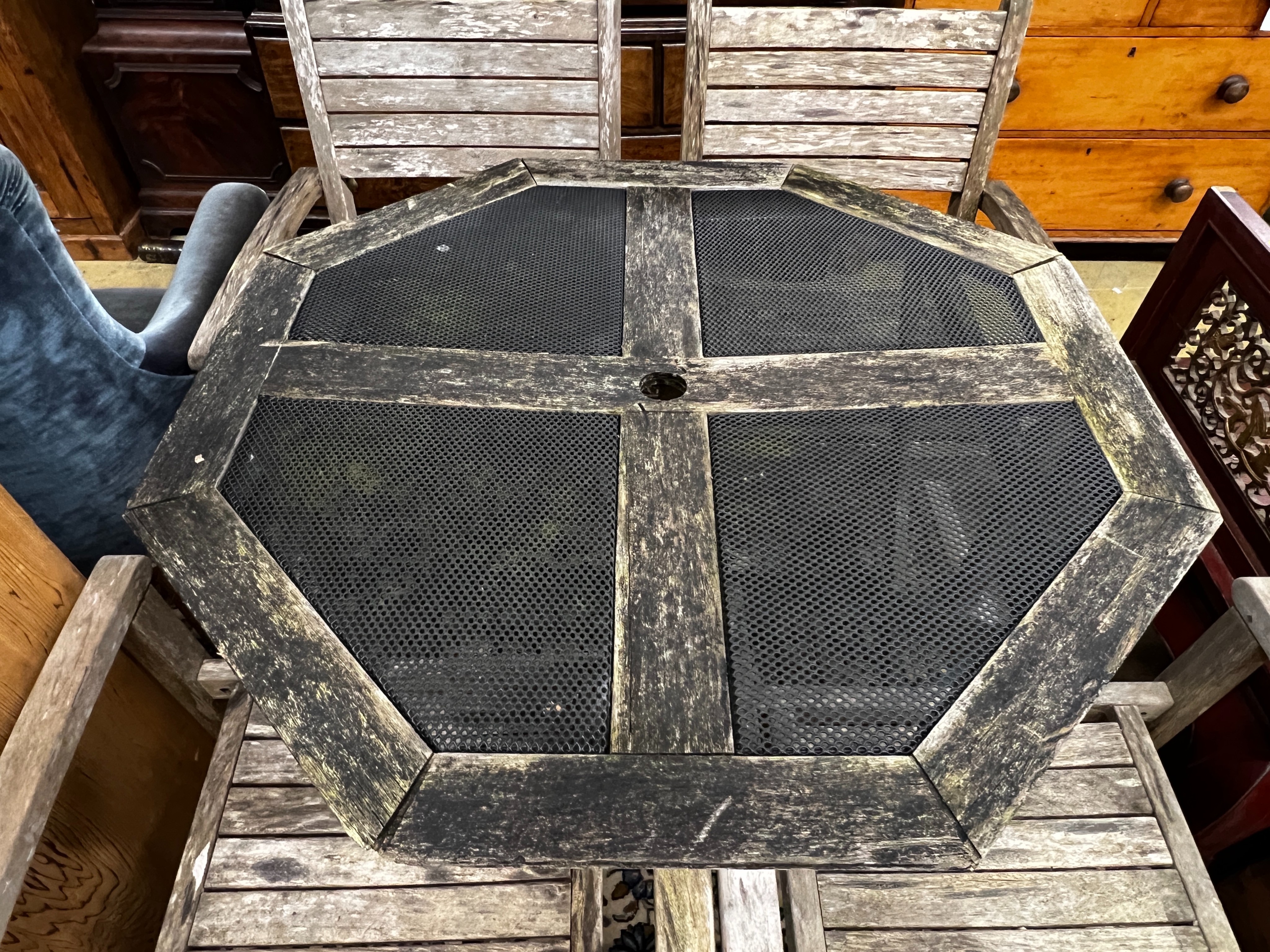 An octagonal weathered teak and mesh garden table, length 103cm, height 74cm together with four teak elbow chairs